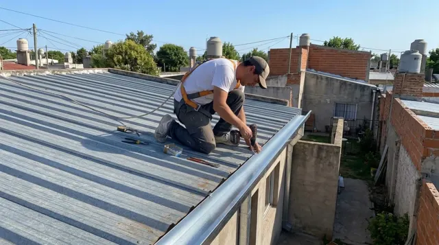 Techista con arnés colocando una canaleta en el borde de un techo de chapa