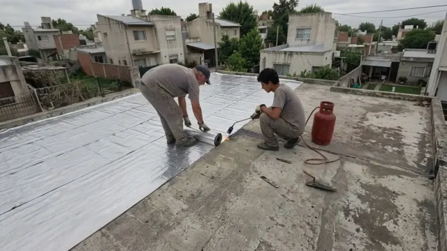 Dos techistas colocando membrana asfáltica con aluminio y soplete sobre la losa de una terraza